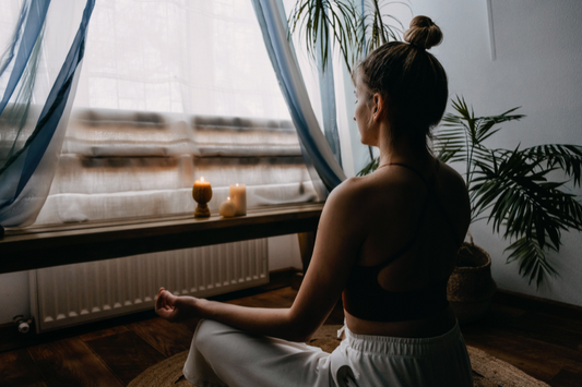 15 Minute Guided Meditation | Strength & Grounding In Stressful Times - Woman facing out her window in meditation with candles burning on the window sill